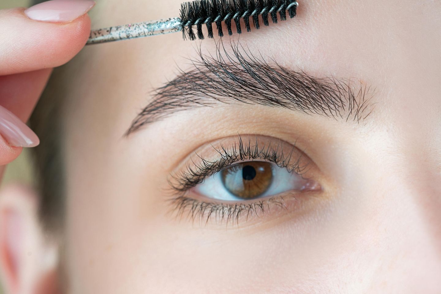 Wachsen Augenbrauen nach?: Eine Frau bürstet ihre rechte Augenbraue nach oben