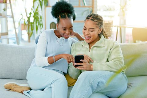 Zwei Frauen schauen gemeinsam auf ein Smartphone: 5 Gewohnheiten von Menschen, die offen sind