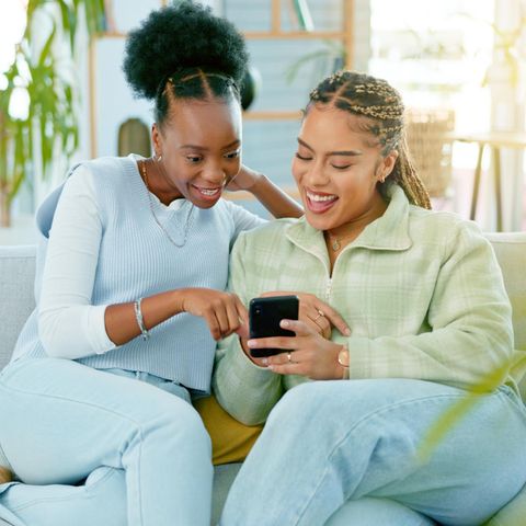 Zwei Frauen schauen gemeinsam auf ein Smartphone: 5 Gewohnheiten von Menschen, die offen sind