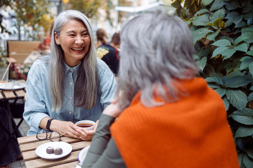 Zwei Frauen sprechen im Café: 5 Körpersprache-Tricks, mit denen andere dich sofort sympathischer finden