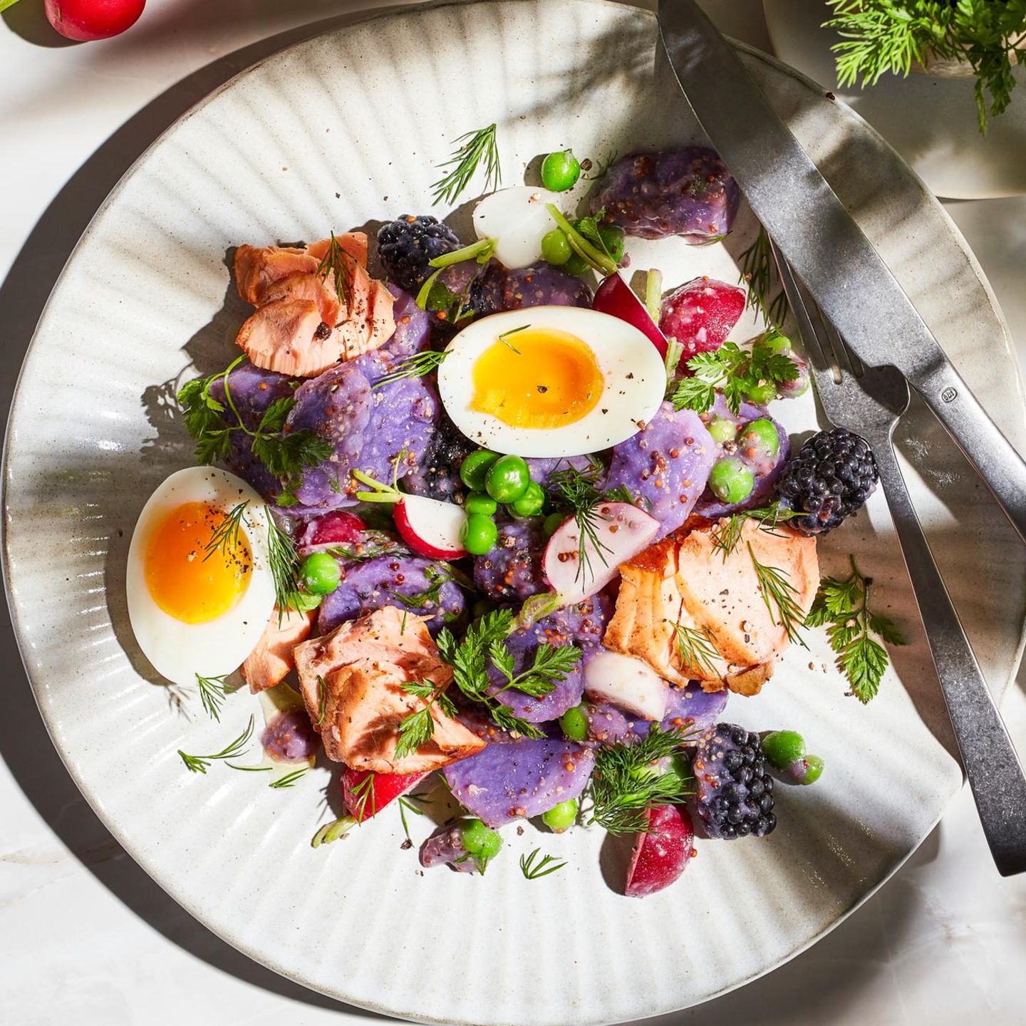 Purple potato salad with peas, egg and flame-grilled salmon