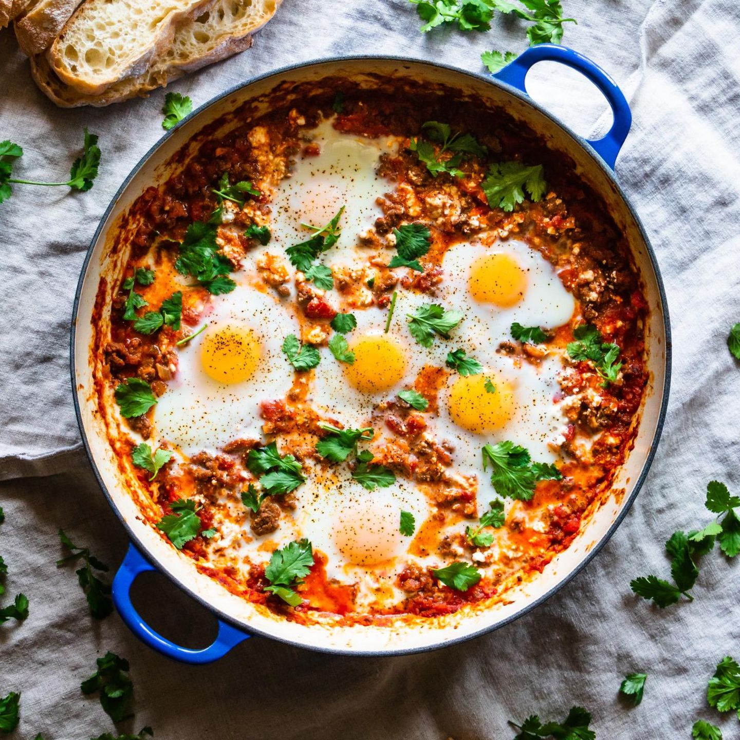 Shakshouka in blauer Pfanne mit Baguette daneben