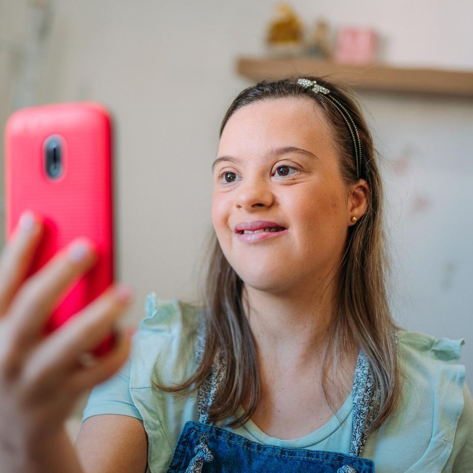 Mädchen mit Down-Syndrom Handy haltend