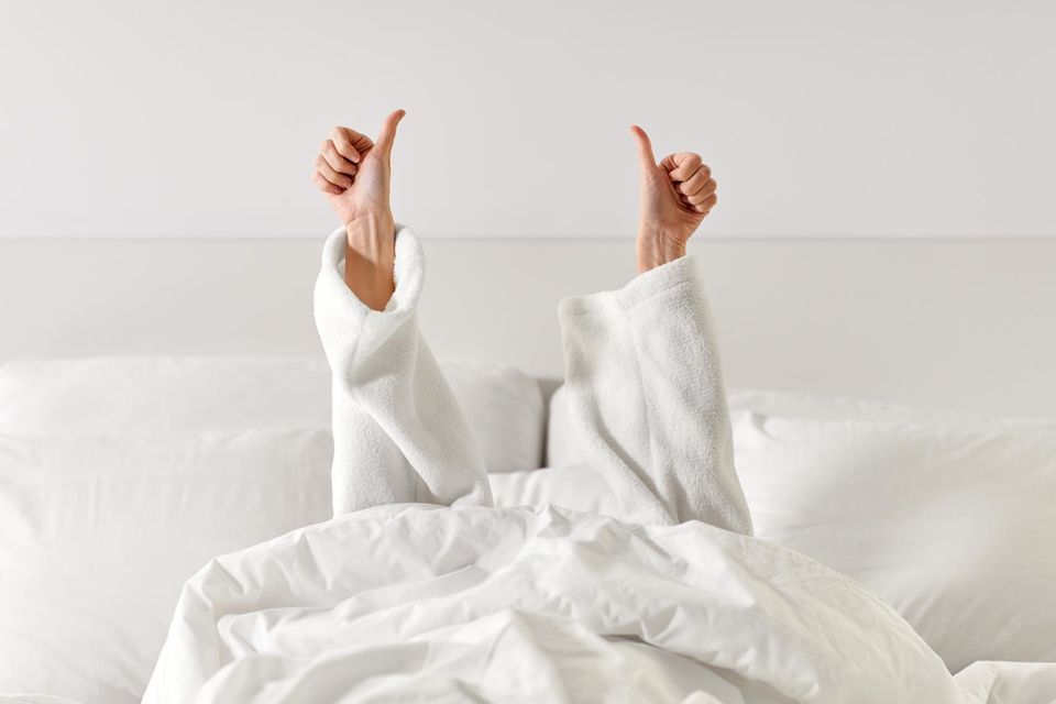 Frau im Bett Daumen in die Luft reckend