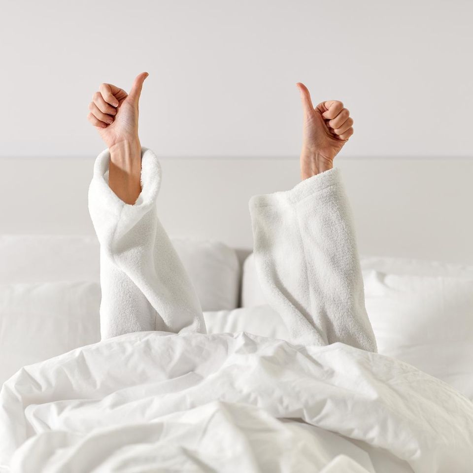 Frau im Bett Daumen in die Luft reckend