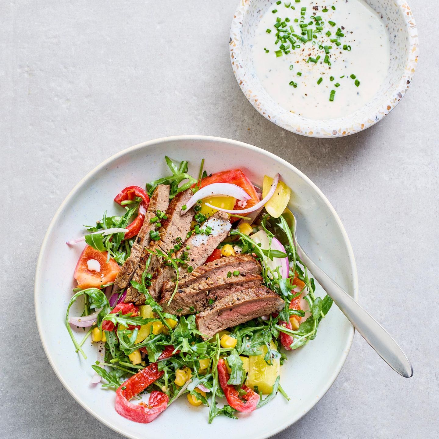 Colorful salad with steak strips and sour cream dressing
