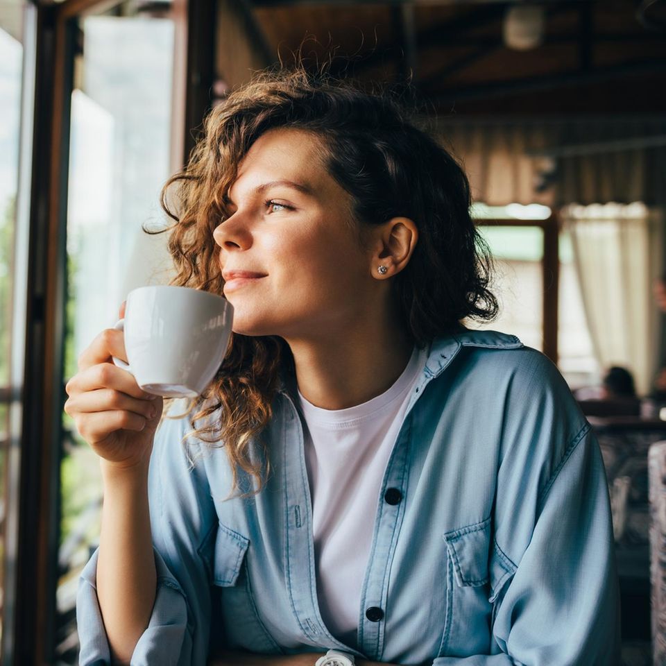 Frau schaut im Café aus dem Fenster: Wie Introvertierte Verbindung und Gemeinschaft finden, ohne auszubrennen