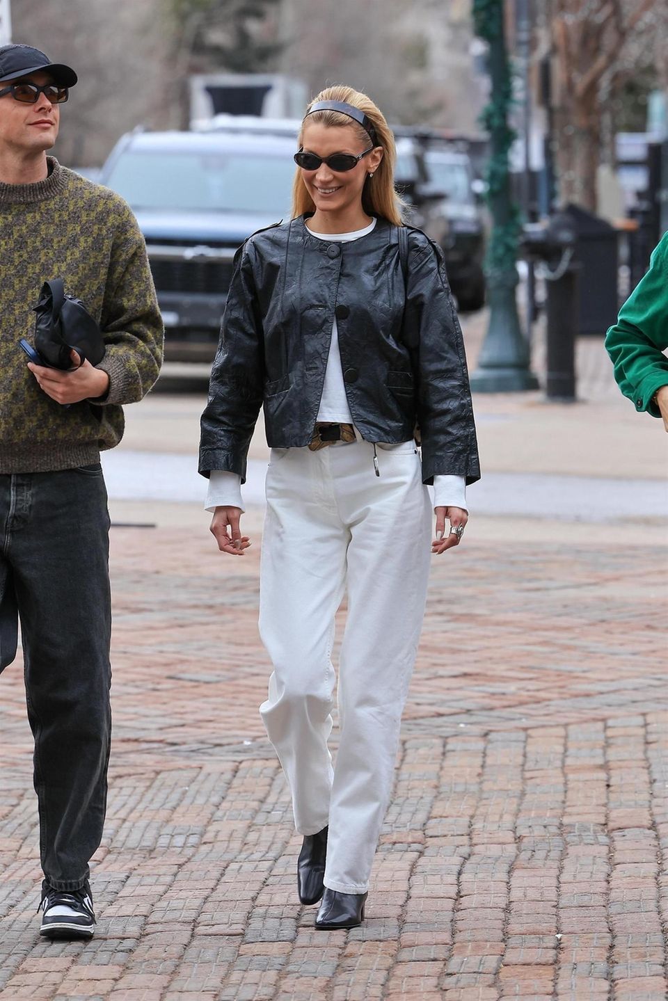 Bella Hadid recently delivered the perfect modern homage to minimalism à la Carolyn Bessette-Kennedy: she combined loose-fitting white jeans with a boxy leather jacket and pointed black boots – understated, yet maximally effective. The look was completed with a wide headband and narrow sunglasses, perfectly capturing the unmistakable 90s CBK vibe.