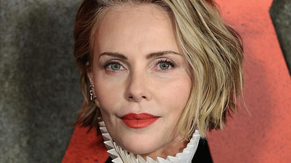Charlize Theron trägt einen tiefen Seitenscheitel und ihre Haare in wilden Beachwaves. 