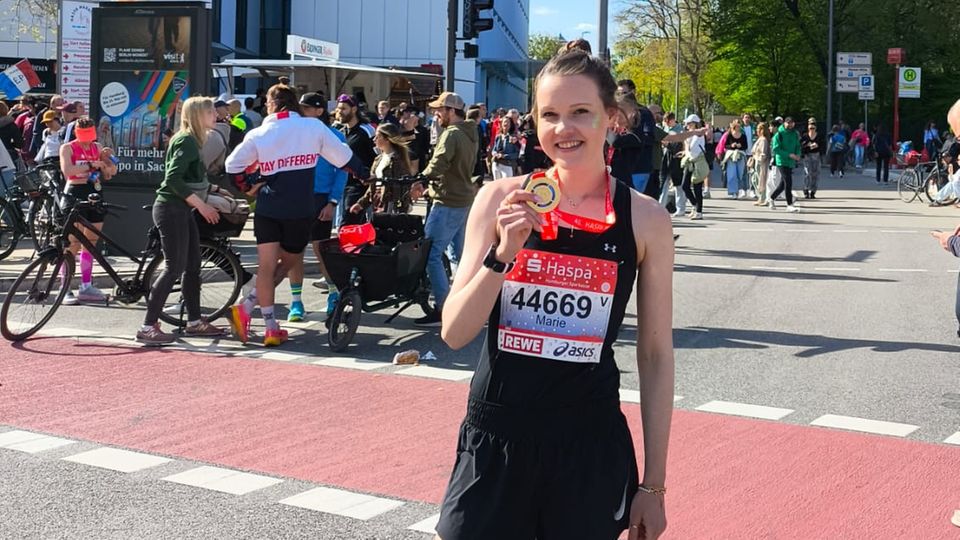 Marie Micke hält nach einem Marathon ihre Medaille hoch