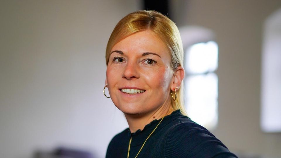 Trauerbegleiterin Kathrin Benkenstein lächelnd auf grauem Sofa